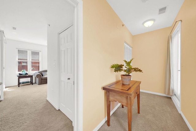 hall with carpet floors, visible vents, and baseboards