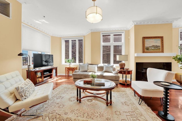 living area featuring wood finished floors, a fireplace, baseboards, ornamental molding, and visible vents