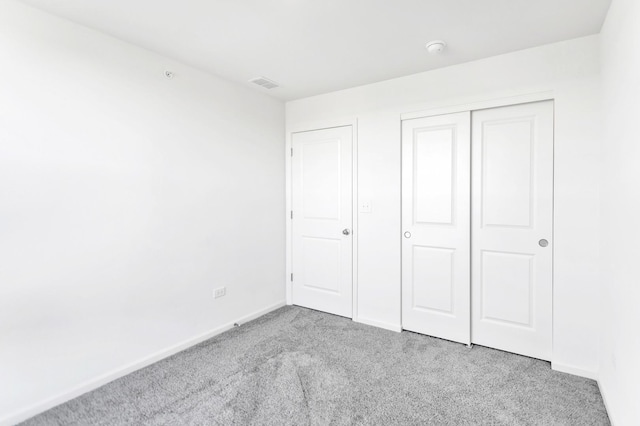 unfurnished bedroom featuring a closet, carpet flooring, baseboards, and visible vents