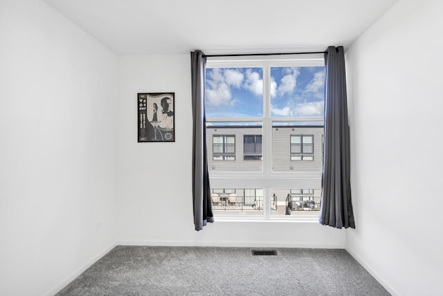 empty room with carpet, visible vents, baseboards, and a healthy amount of sunlight