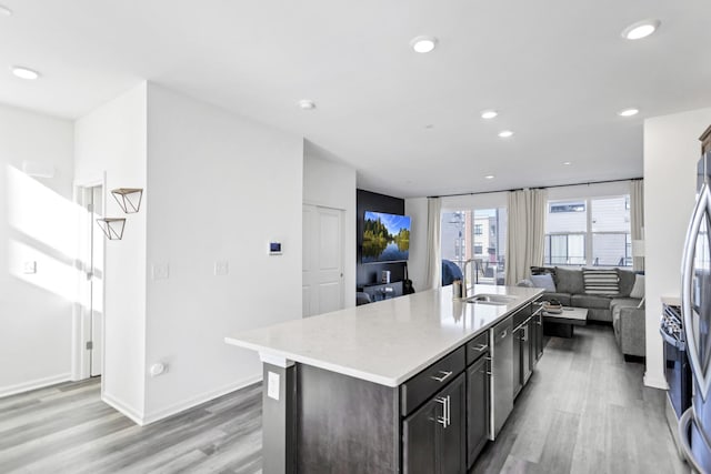 kitchen with open floor plan, light wood-style floors, light countertops, and a sink