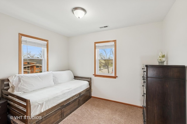 living area with baseboards, plenty of natural light, carpet flooring, and visible vents