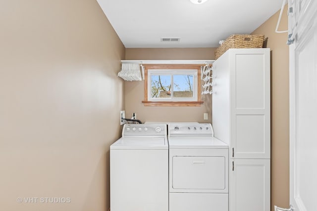 clothes washing area with washing machine and dryer, cabinet space, and visible vents