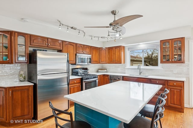 kitchen with a sink, appliances with stainless steel finishes, a kitchen breakfast bar, and light countertops