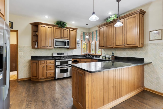 kitchen with a peninsula, a sink, dark countertops, and stainless steel appliances