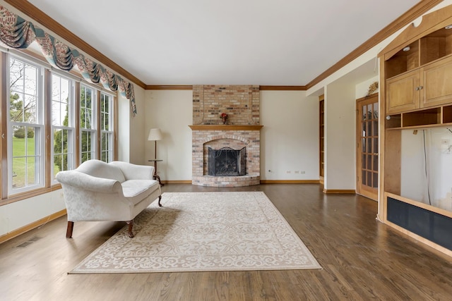living area with baseboards, ornamental molding, a brick fireplace, visible vents, and wood finished floors