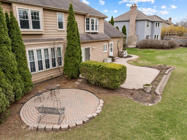rear view of house with a lawn, a patio area, and a shingled roof