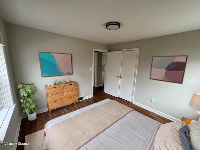 bedroom with visible vents, baseboards, dark wood-style floors, and a closet