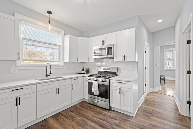 kitchen featuring white cabinetry, light countertops, a sink, stainless steel appliances, and decorative backsplash