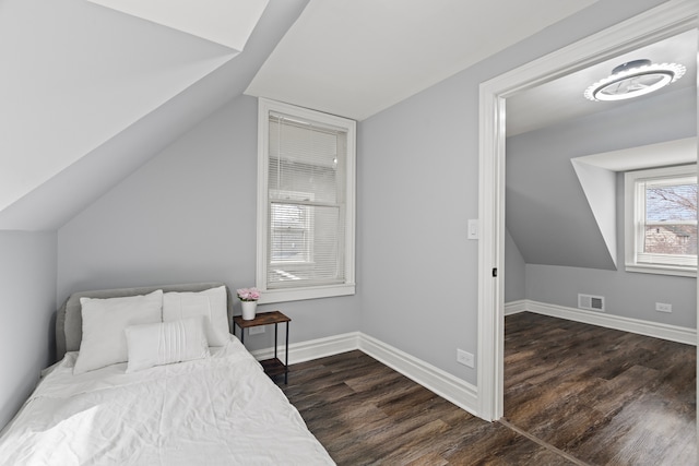 bedroom with lofted ceiling, visible vents, baseboards, and wood finished floors