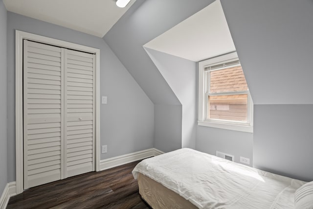 bedroom featuring dark wood-type flooring, a closet, vaulted ceiling, visible vents, and baseboards