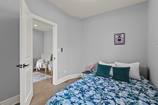 bedroom featuring wood finished floors, baseboards, and visible vents