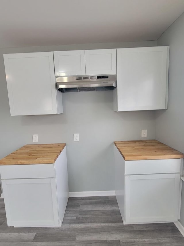 kitchen featuring butcher block counters, white cabinets, and under cabinet range hood