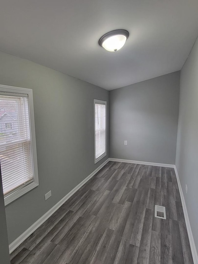 unfurnished room with visible vents, baseboards, and dark wood finished floors