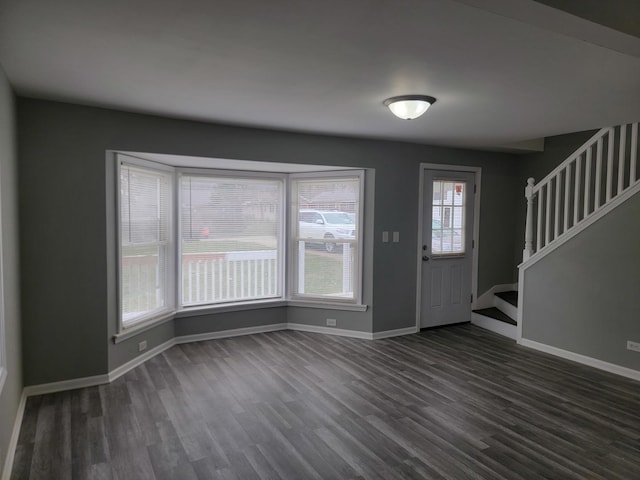 foyer entrance featuring baseboards, stairs, and dark wood finished floors