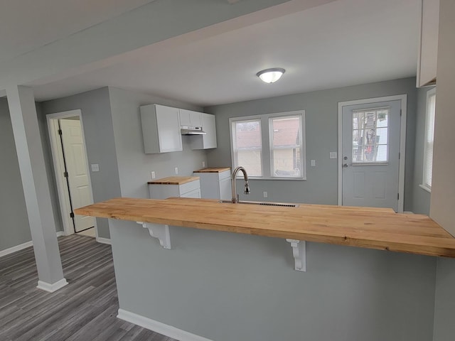 kitchen with butcher block counters, a sink, baseboards, and a breakfast bar area