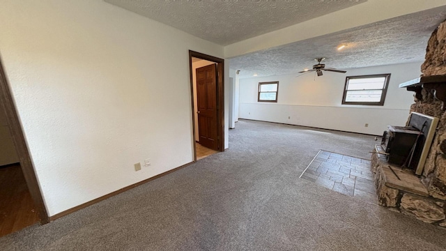 6092 Torch Lite Trl, Loves Park, IL 61111 - unfurnished living room featuring carpet flooring, a textured ceiling, ceiling fan, and a wood stove
