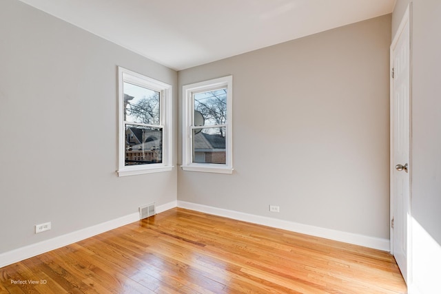 spare room with visible vents, light wood-style flooring, and baseboards