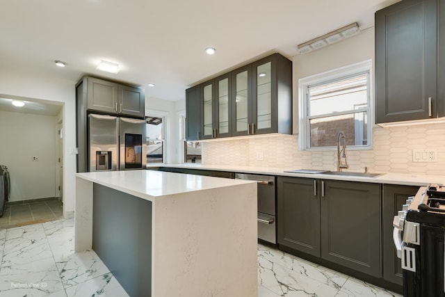kitchen with tasteful backsplash, a sink, stainless steel appliances, marble finish floor, and a kitchen island