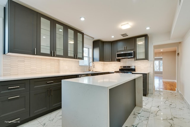 kitchen with a wealth of natural light, visible vents, marble finish floor, a sink, and stainless steel appliances