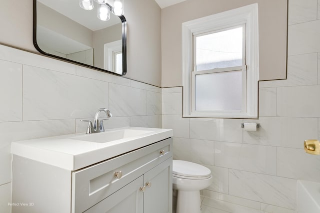 bathroom featuring toilet, a bathing tub, vanity, and tile walls