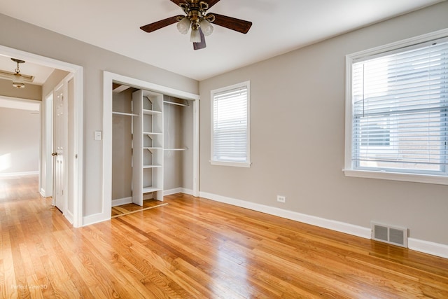 unfurnished bedroom with light wood-type flooring, baseboards, multiple windows, and visible vents