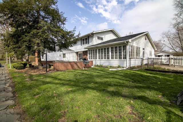 back of property with a sunroom, fence, and a yard
