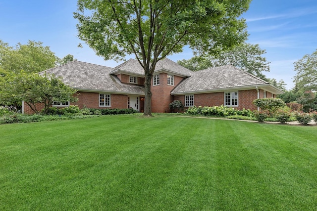 view of front facade with brick siding and a front lawn