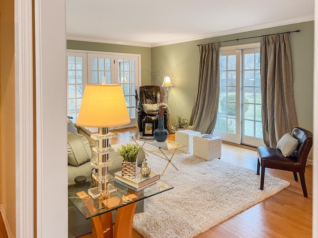 sitting room with ornamental molding and wood finished floors