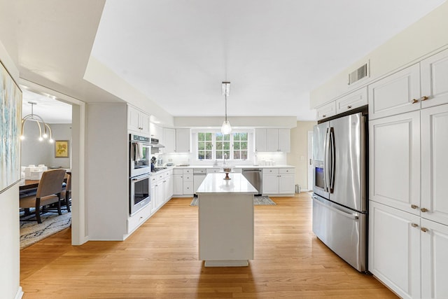 kitchen featuring visible vents, a kitchen island, light wood-type flooring, light countertops, and appliances with stainless steel finishes