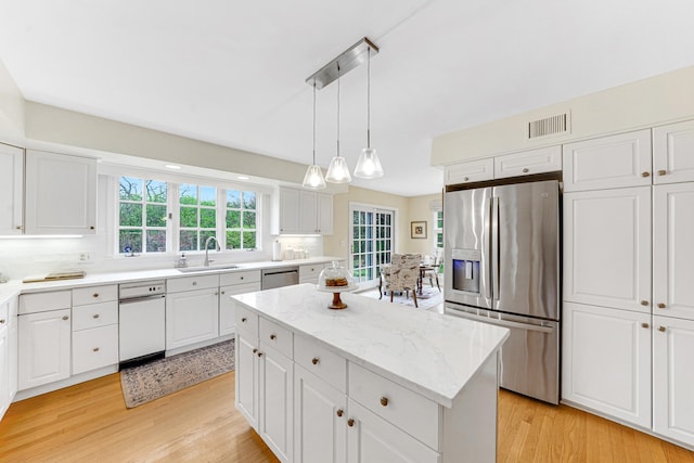kitchen featuring a sink, stainless steel appliances, light wood-style flooring, and white cabinetry