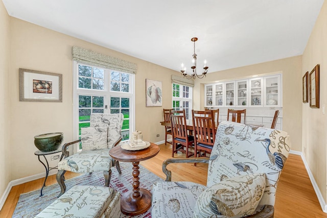 sitting room with baseboards, a wealth of natural light, wood finished floors, and a chandelier