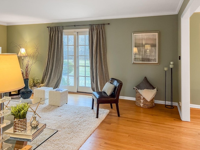 sitting room featuring light wood finished floors, crown molding, and baseboards