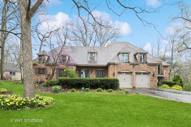french provincial home featuring a garage, aphalt driveway, a front lawn, and brick siding