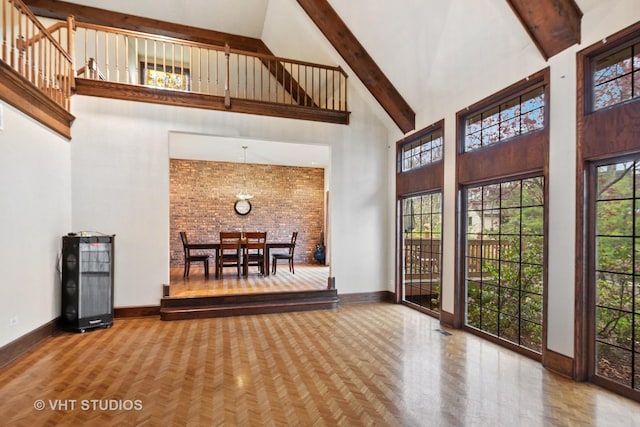 interior space with baseboards, beam ceiling, visible vents, and high vaulted ceiling