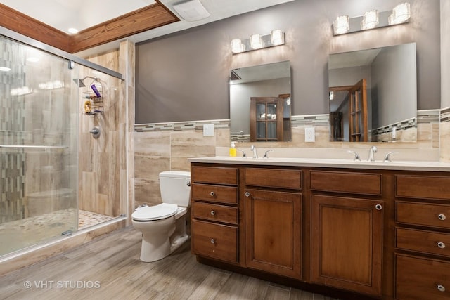 bathroom with double vanity, tile walls, a shower stall, a sink, and toilet