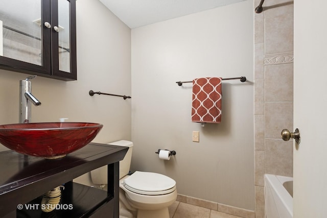 bathroom featuring baseboards, a sink, tile patterned floors, and toilet