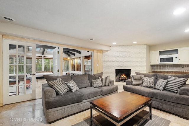 living room with visible vents, recessed lighting, and a brick fireplace