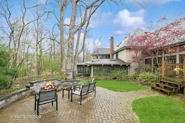 view of patio / terrace with a sunroom, an outdoor fire pit, and a deck