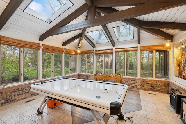 rec room with tile patterned flooring, plenty of natural light, lofted ceiling with skylight, and brick wall