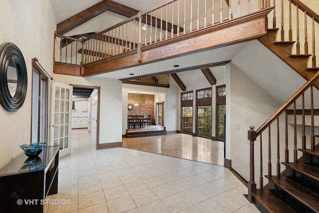 entrance foyer with tile patterned flooring, stairs, beam ceiling, and high vaulted ceiling