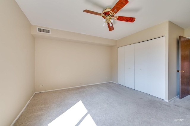 unfurnished bedroom featuring a closet, a ceiling fan, visible vents, light carpet, and baseboards
