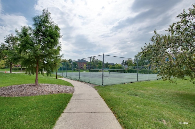 view of tennis court featuring fence and a lawn