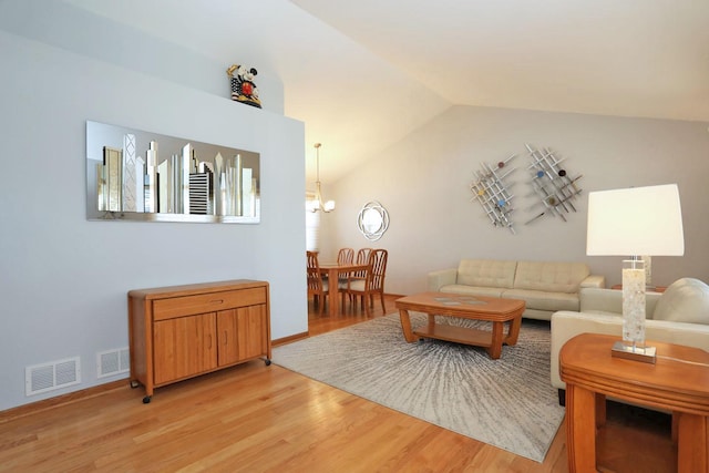 living room featuring light wood finished floors, lofted ceiling, a notable chandelier, and visible vents