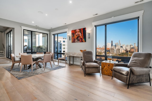 living area featuring a city view, light wood-type flooring, visible vents, and recessed lighting