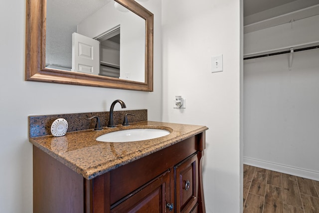 bathroom featuring vanity, baseboards, and wood finished floors