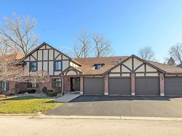 english style home with a garage, stucco siding, brick siding, a front lawn, and driveway