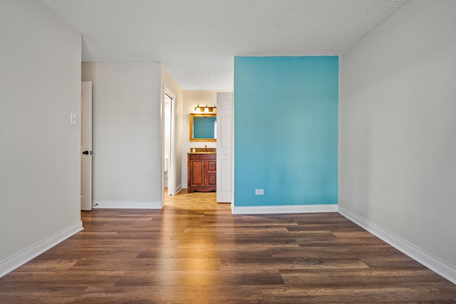 interior space with a textured ceiling, wood finished floors, and baseboards