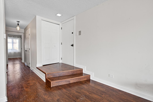 corridor featuring baseboards, a textured ceiling, and wood finished floors