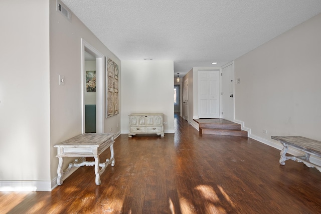 interior space with visible vents, baseboards, wood finished floors, and a textured ceiling